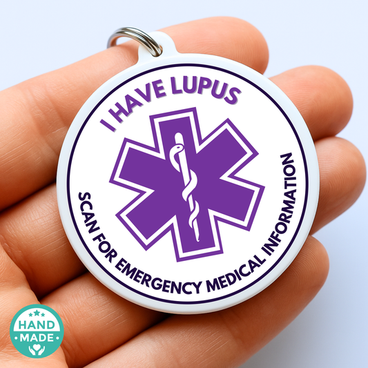 Round medical alert tag with 'I have Lupus' text and emergency symbol held in a hand.