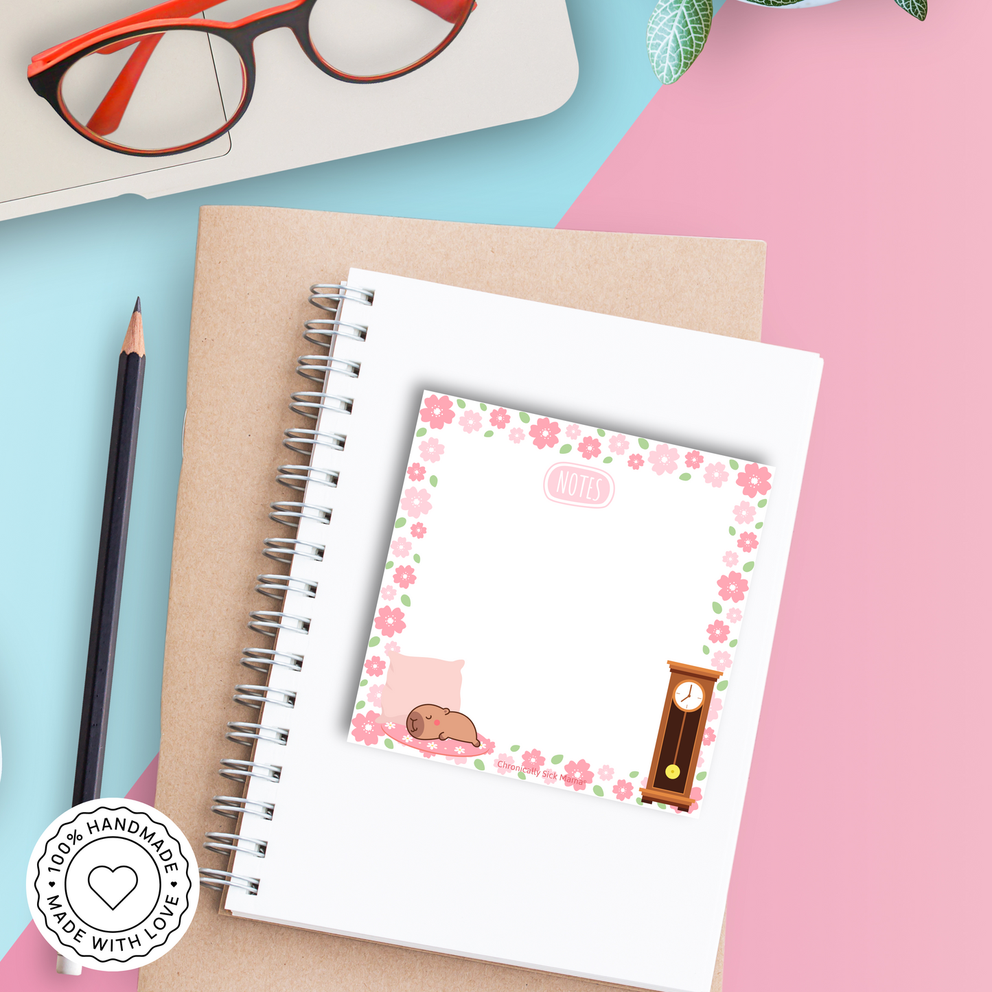 Notebook with a decorative card featuring a capybara and clock on a colourful floral background