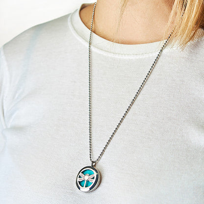 Person wearing a necklace with a circular pendant on a plain Dragon Fly background